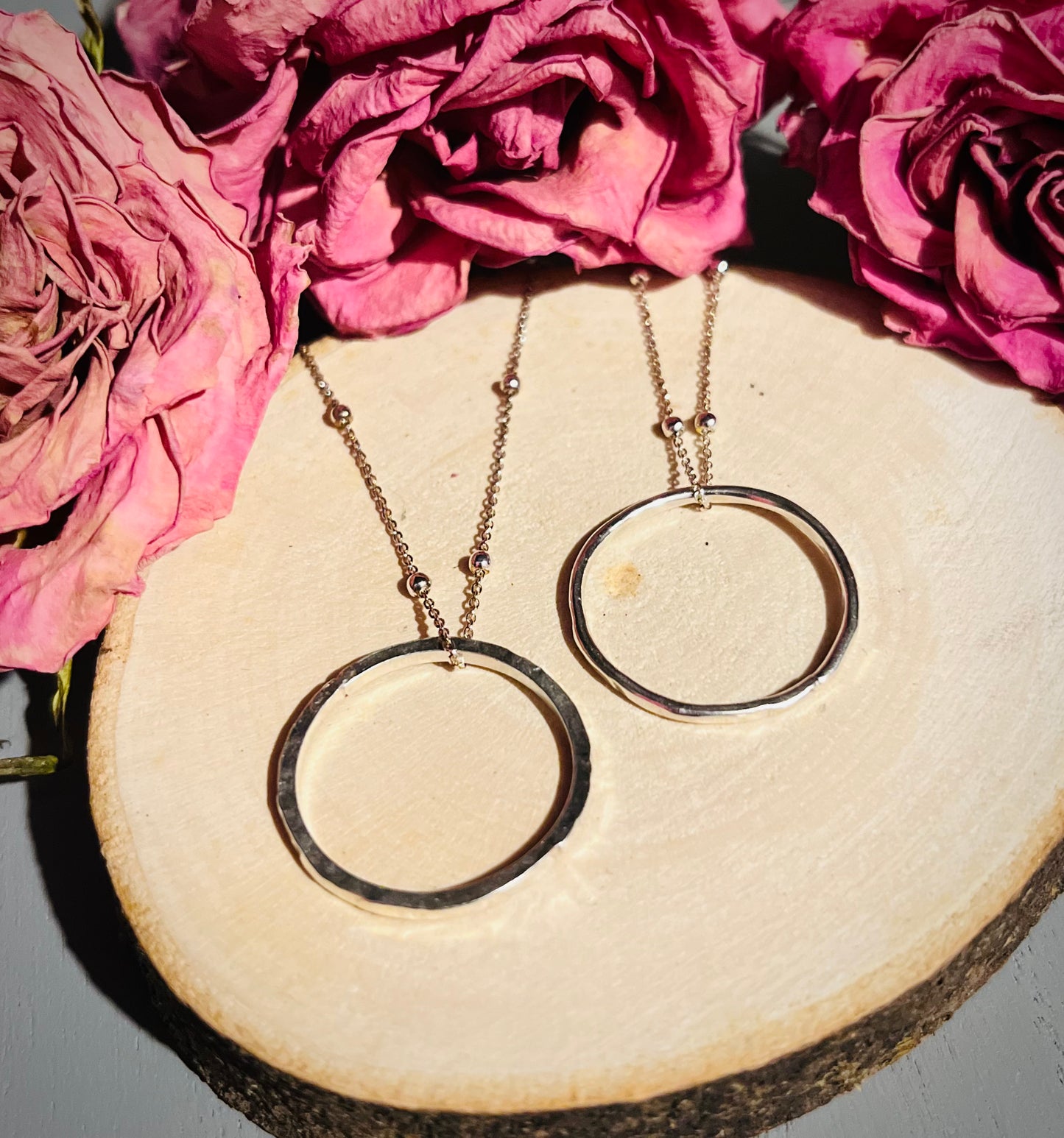 Two silver halo circle pendants on a wooden background | Silverlicious Artisan Jewellery